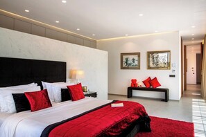 Een moderne hotelkamer met een groot bed, een nachtkastje, een bankje en kunst aan de wanden.