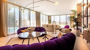 Ein modernes Wohnzimmer mit einem violetten Sofagarnitur, einem runden Couchtisch und einem minimalistischen Design.