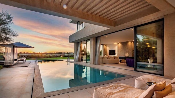 Ein moderner Poolbereich im Freien mit einer Sitzecke und einem Fernseher im Hintergrund.