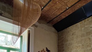 Une chambre à coucher avec un lit, un fauteuil vert, une table et un mur orné d’une fresque.