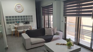 A modern living room with a sofa, coffee table, and a dining area with a table and chairs. - Academys Modern Apartments by Athens Urban Retreat (Athens)