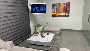 A modern living room with a grey sofa, a coffee table with decorative items, a flat-screen TV, and two paintings on the wall. - Academys Modern Apartments by Athens Urban Retreat (Athens)
