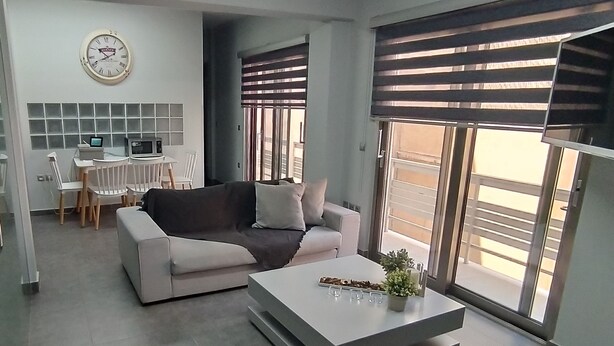A modern living room with a sofa, a coffee table, and a dining area with chairs and a table. - Academys Modern Apartments by Athens Urban Retreat (Athens)