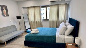 A modern hotel room with a bed, a sofa, a small table, and a mirror. - Academys Modern Apartments by Athens Urban Retreat (Athens)