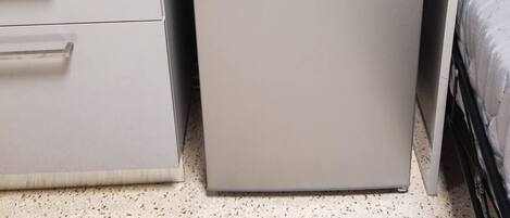 Una kitchenette compacta con una encimera, una cafetera y un refrigerador pequeño.