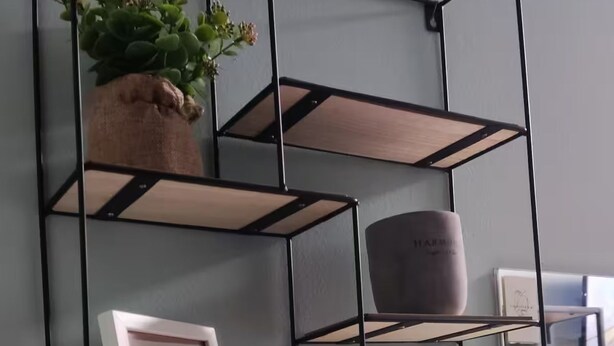 A wall-mounted metal shelving unit with multiple compartments, some containing decorative items like a potted plant and a framed picture. - Praxitelous Apartments by Athens Urban Retreat (Athens)