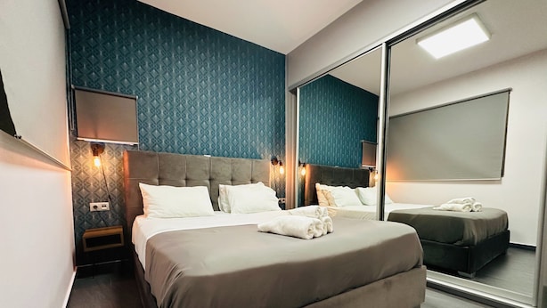 Ein modernes Hotelzimmer mit einem großen Bett, einem Nachttisch, einem Spiegel und einer Wandleuchte.