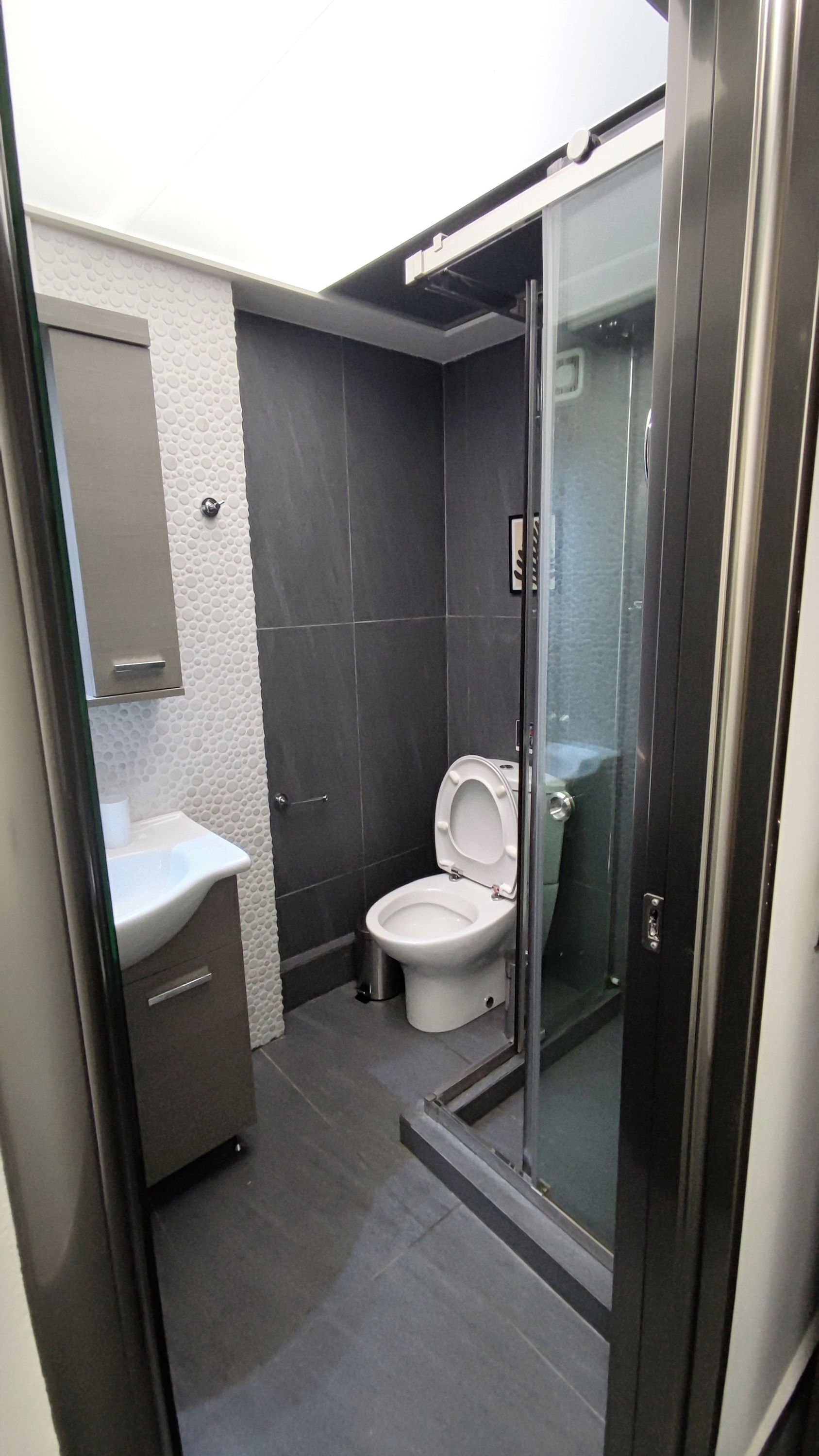 Un baño moderno con inodoro, lavabo y cabina de ducha de vidrio.