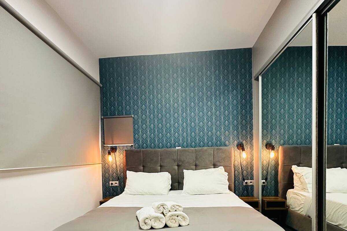 Ein modernes Hotelzimmer mit einem großen Bett, einem Oberlicht und einem großen Spiegel.