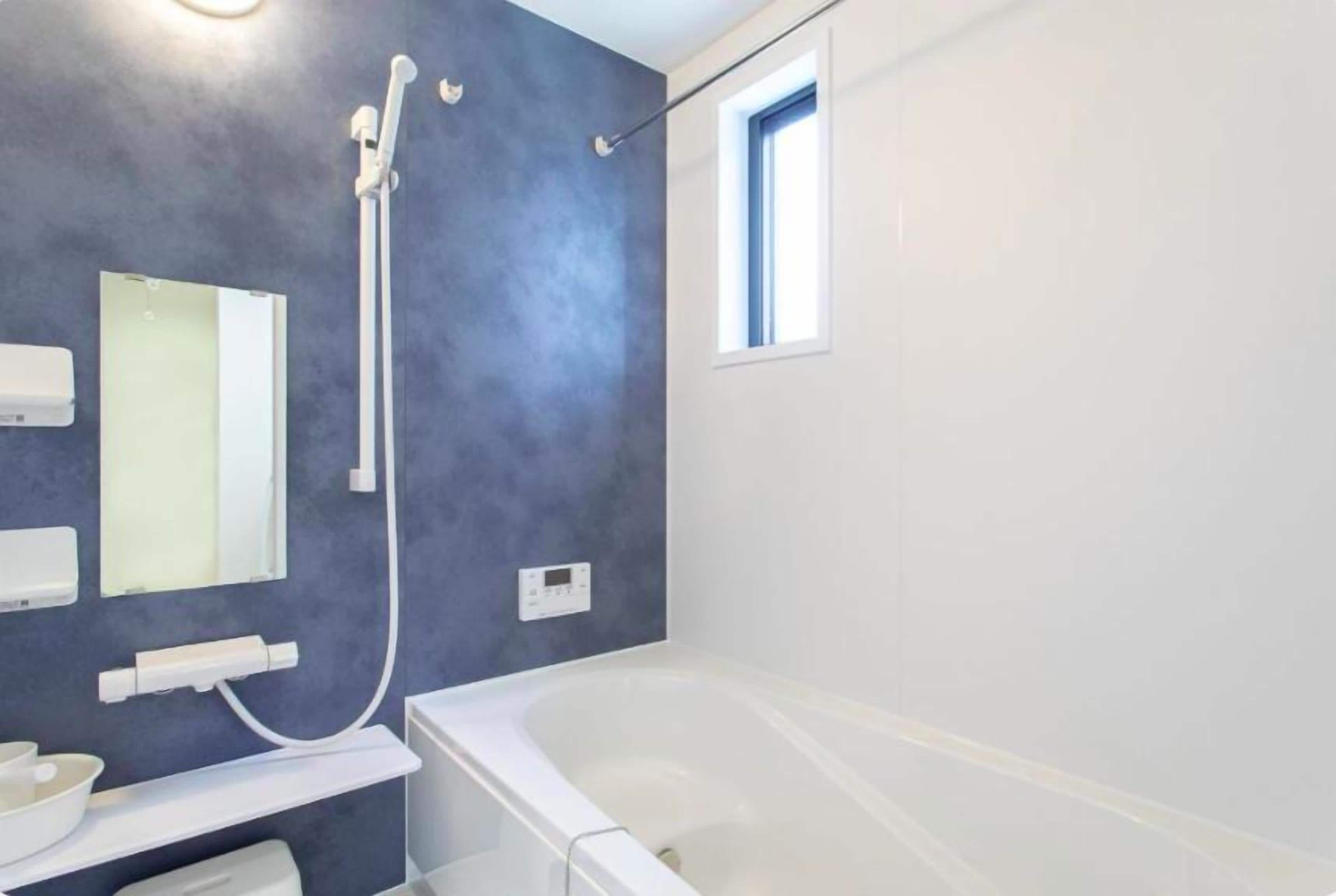 Un baño moderno con bañera, ducha de mano, espejo y ventana.