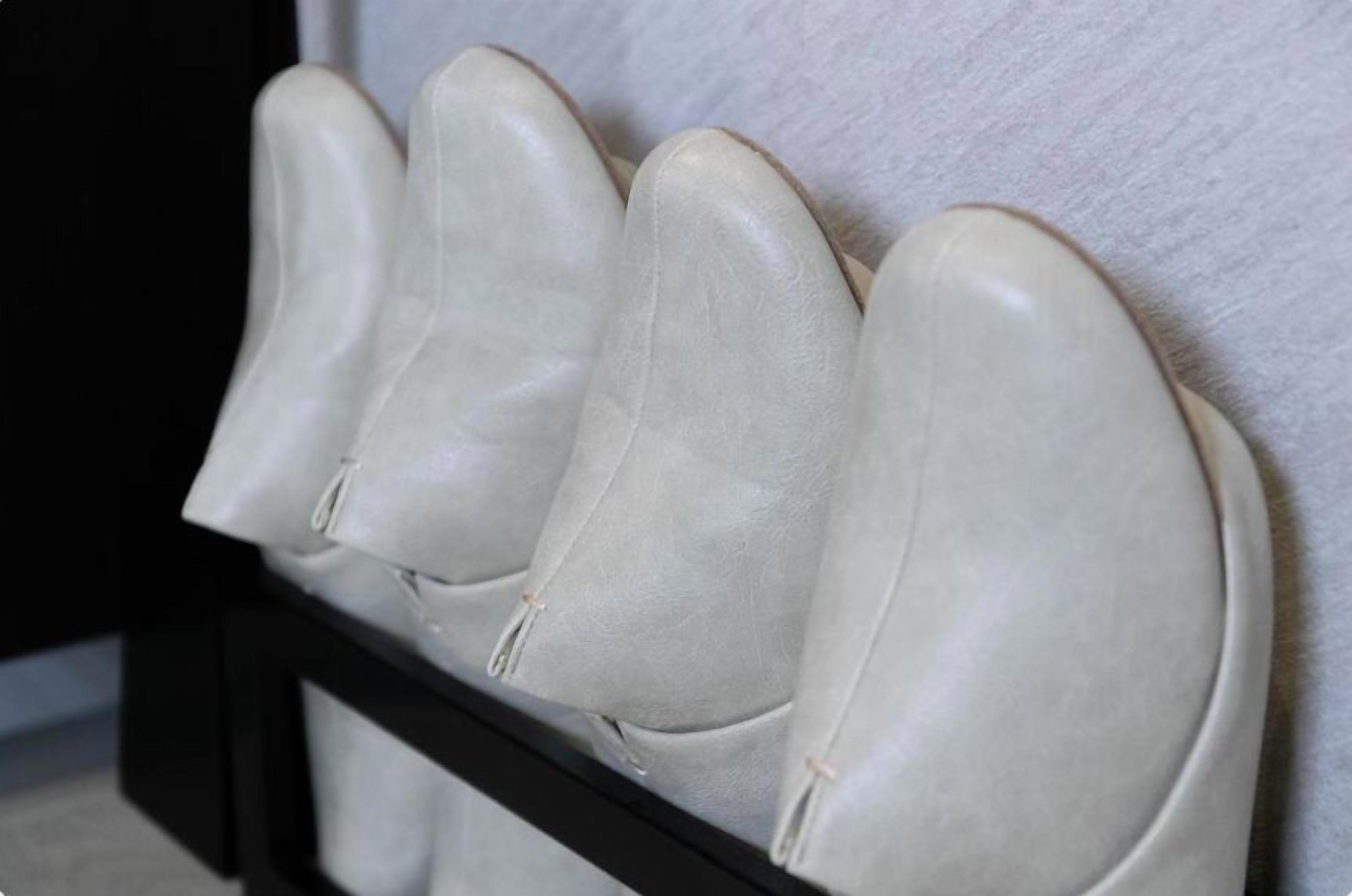 A set of four white cushioned headrests against a wall.
