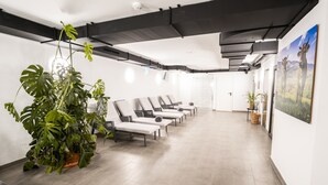 A modern waiting area with lounge chairs, large potted plants, and a painting on the wall.