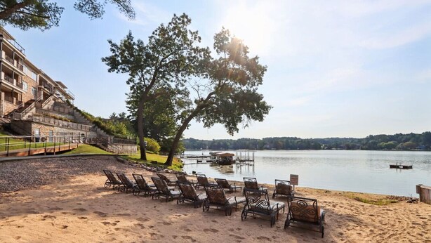 A beach with sun loungers and a view of a lake. - Beachtop Condo at Delton Grand - Waterfront (Wisconsin Dells)