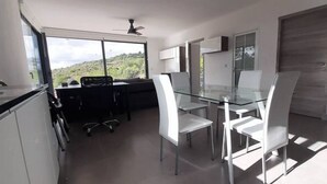 A modern kitchen with a glass dining table and chairs, a black office chair, and a view of a green landscape through large windows. - Casa da Alfarrobeira-Villa 4+2P Pool & View (São Bartolomeu de Messines)