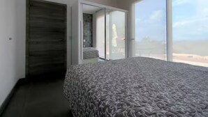 A bedroom with a large bed, a sliding glass door leading to a balcony, and a dark wooden door. - Casa da Alfarrobeira-Villa 4+2P Pool & View (São Bartolomeu de Messines)