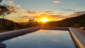 A swimming pool at sunset with a clear sky and wind turbines in the background. - Casa da Alfarrobeira-Villa 4+2P Pool & View (São Bartolomeu de Messines)