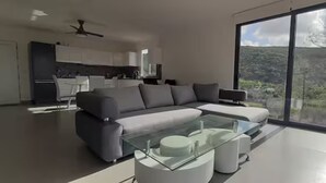 A modern living room with a glass coffee table, grey sofa, and a view of a mountainous landscape through large windows. - Casa da Alfarrobeira-Villa 4+2P Pool & View (São Bartolomeu de Messines)