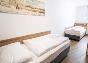 A bedroom with two beds, wooden headboards, and a painting on the wall. - Apartment in Fieberbrunn With Balcony (Fieberbrunn)