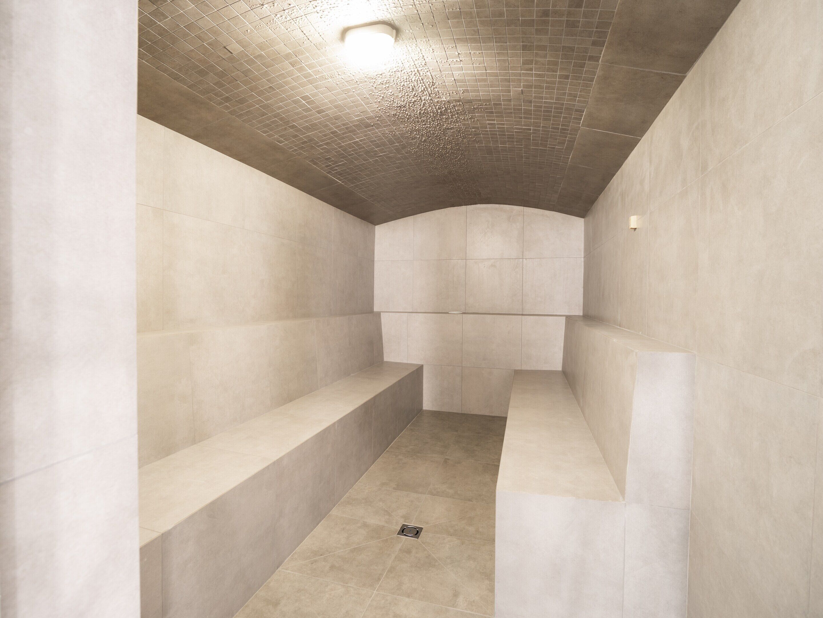 A modern bathroom with a tiled floor, a shower area, and a built-in bench.