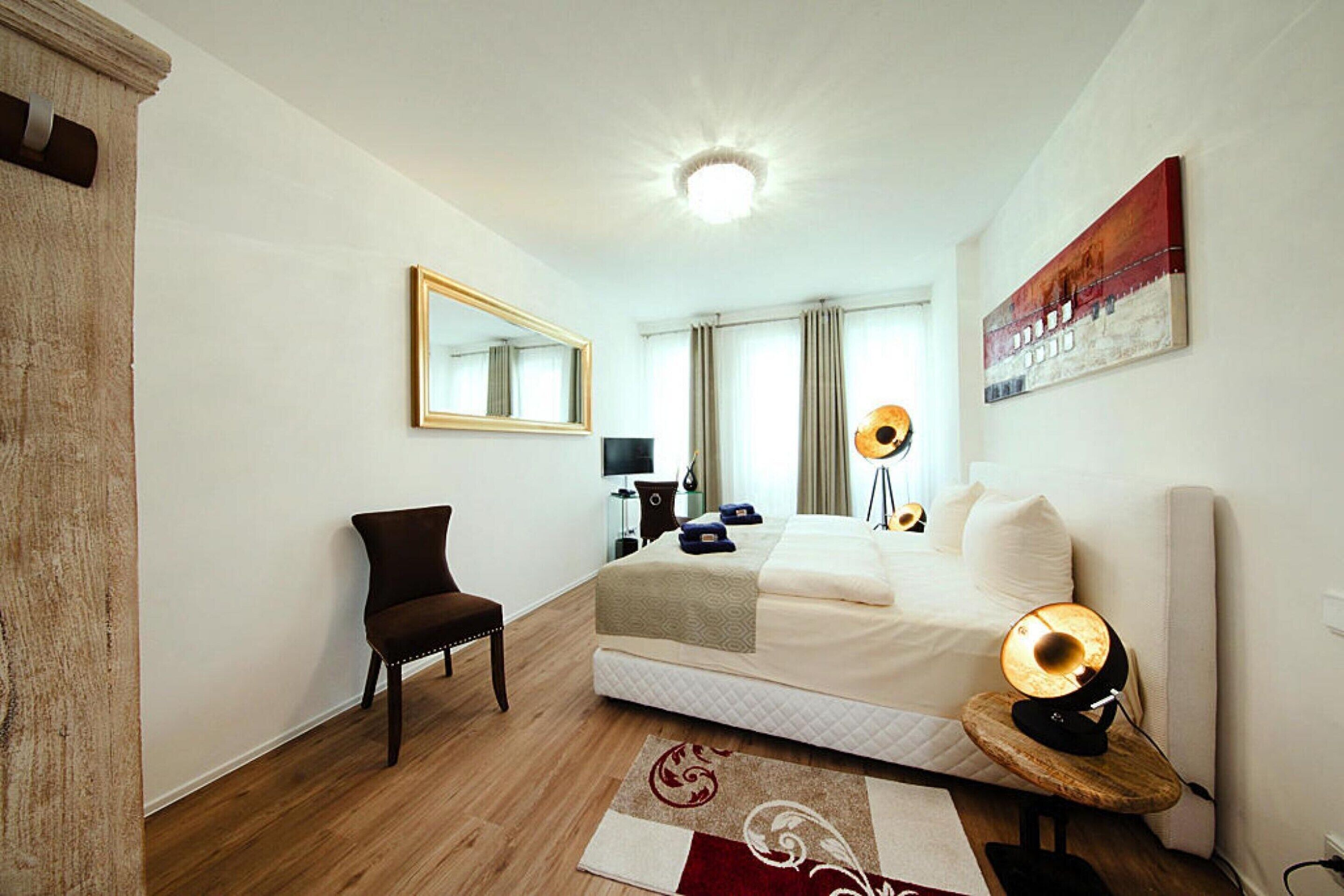 Ein Hotelzimmer mit Bett, Stuhl, Schreibtisch, Lampe und einem Bild an der Wand.