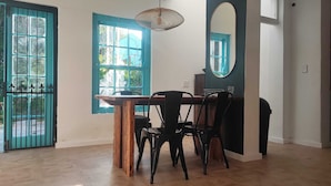Ein Essbereich mit Holztisch und Stühlen, einer hängenden Leuchte und einem großen Spiegel an der Wand.