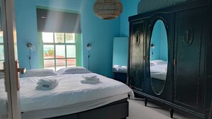 Ein Schlafzimmer mit Bett, Kleiderschrank, Fenster und einer Wandleuchte.