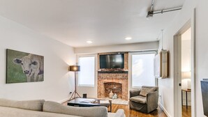 Una sala de estar moderna con chimenea, un sofá, una mesa de centro y un televisor sobre la chimenea.