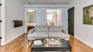 Una sala de estar moderna con un sofá gris, una mesa de centro con revistas y un televisor de pantalla plana montado en la pared.
