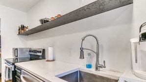Una cocina moderna con electrodomésticos de acero inoxidable, un lavamanos doble y una cafetera.