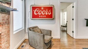 Un interior moderno con un cartel de Coors Beer, una pared de ladrillo y un suelo de madera.