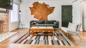 A modern living room with a leather wall art, a sofa, a coffee table, and a white chair.
