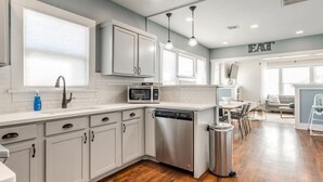 Una cocina moderna con armarios blancos, electrodomésticos de acero inoxidable y piso de madera.