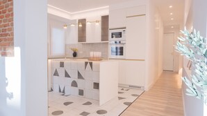Une cuisine moderne avec des meubles blancs, un îlot central et des appareils électroménagers intégrés.