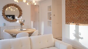 Un salon moderne avec un canapé blanc, une table à manger en bois et un grand miroir.