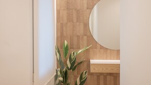 Une salle de bain avec un mur en bois, un lavabo blanc et un miroir.