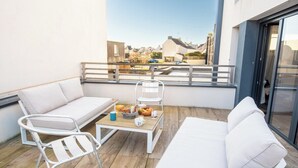 A balcony with a white sofa, a white chair, and a small table with fruits and cups. - Beautiful villa in Lomener-beach, restaurants, and shops within walking distance (Ploemeur)