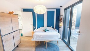 Un dormitorio con cama, armario, alfombra redonda y un ventanal grande.