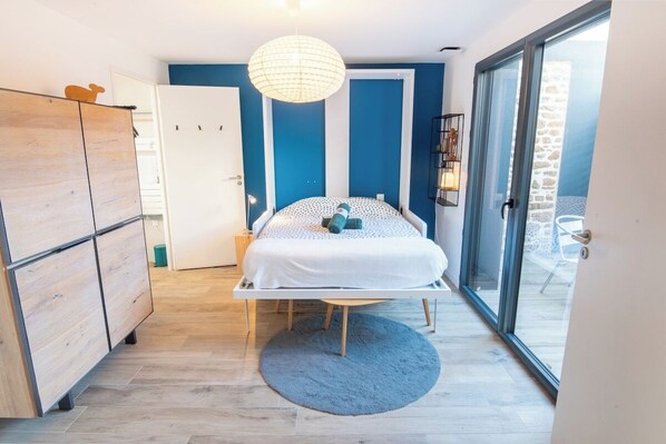 A bedroom with a bed, a wardrobe, a round rug, and a large window.