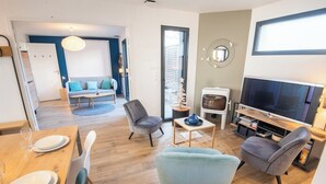 Una sala de estar moderna con un sofá, sillas, televisor y un comedor con mesa y sillas.
