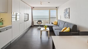 A modern apartment with a kitchen, dining area, and a balcony with a view of the sea. - Spacious Studio With sea View (Blankenberge)