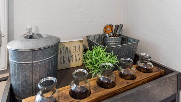 A bar area with rustic decor, including metal letters spelling "BAR" on the wall, a wooden tray with glass jars, and a sign that reads "NEVER STOP DREAMING." - Charming Downtown Bungalow | Easy Airport Access (San Diego)