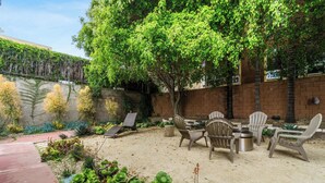 A patio with outdoor seating, a brick wall, and a variety of plants. - Charming Downtown Bungalow | Easy Airport Access (San Diego)