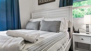A neatly made bed with patterned pillows, a bedside table with a clock, and a 'RELAX' sign on the wall. - Charming Downtown Bungalow | Easy Airport Access (San Diego)