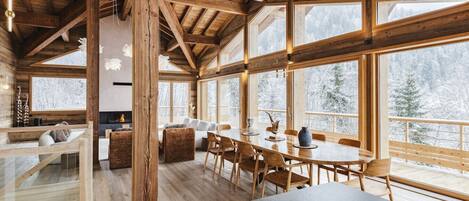 Eine geräumige Holzhütte mit großen Fenstern, einem Essbereich und einem Kamin.
