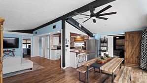 Una cocina moderna con una isla central, suelo de madera y ventilador de techo.