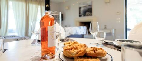 A dining table with a bottle of wine, a plate of pastries, and glasses.