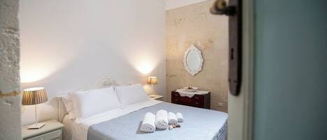 A hotel room with a bed, bedside tables, a mirror, and a door.