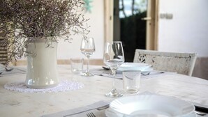 A dining table set with white plates, clear glasses, and a vase with dried flowers. - Villa La Tonnara (Porto Cesareo)