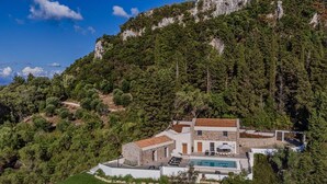 Uma casa moderna com piscina, cercada por vegetação exuberante e montanhas.