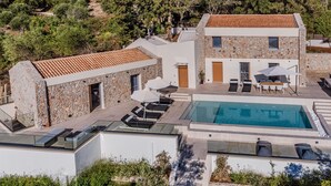 Uma villa moderna com piscina, área de estar ao ar livre e fachada de pedra.